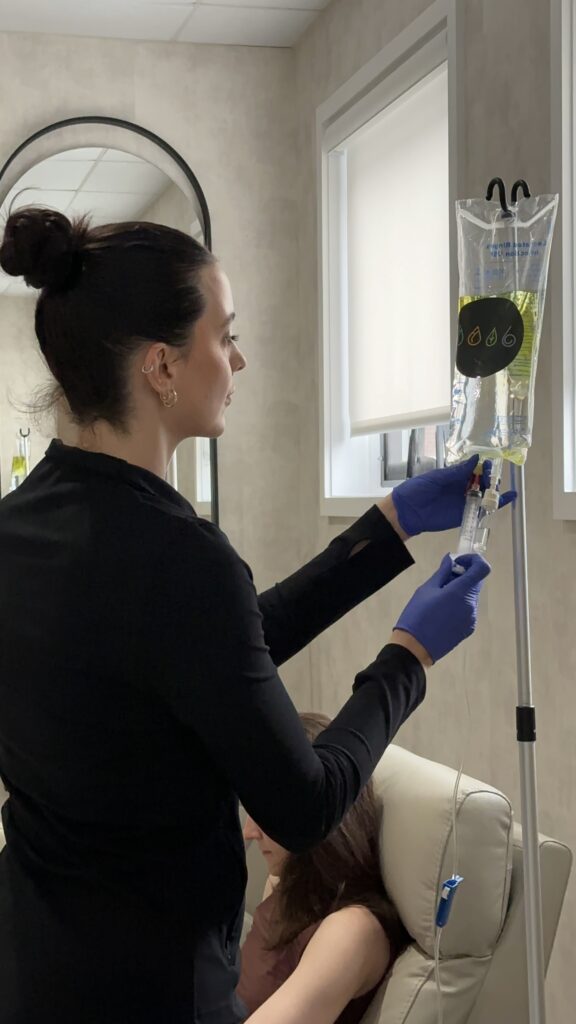 Nurse adding to IV bag while patient sits in chair