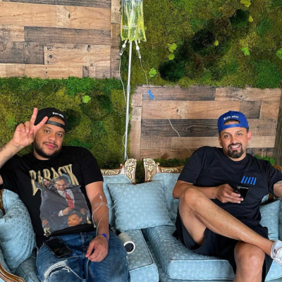 2 men sitting on couch together while receiving IV therapy treatments