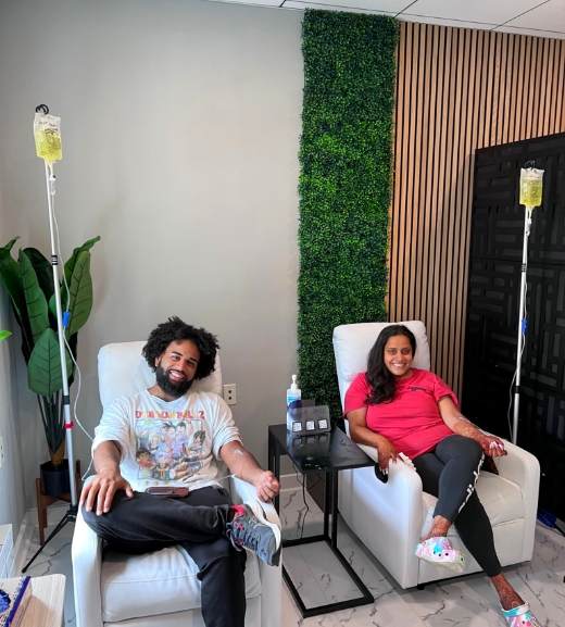 Man and woman sitting in chairs while receiving IV therapy treatment at IV Elements