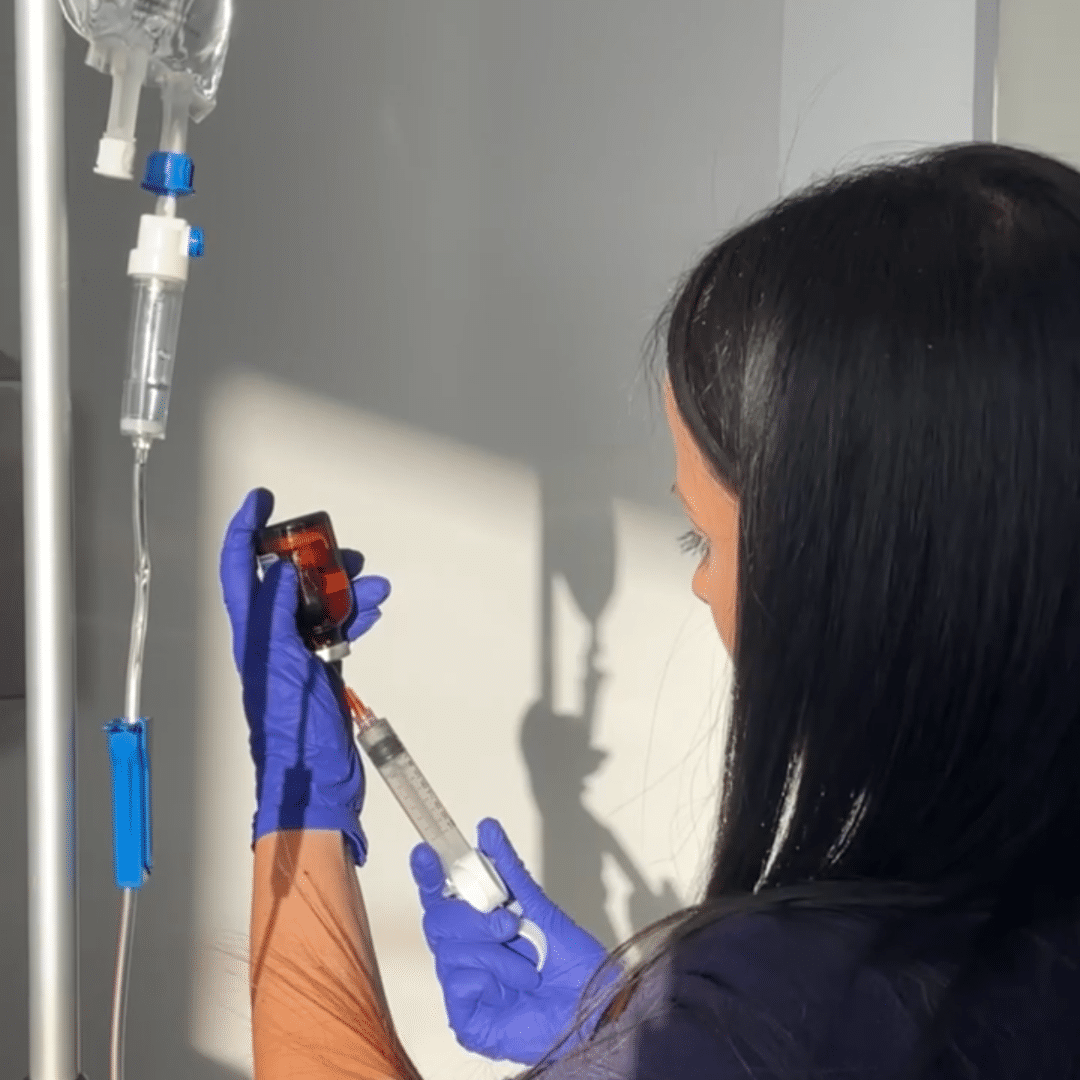 Nurse from IV Elements adding vial of vitamins to IV bag