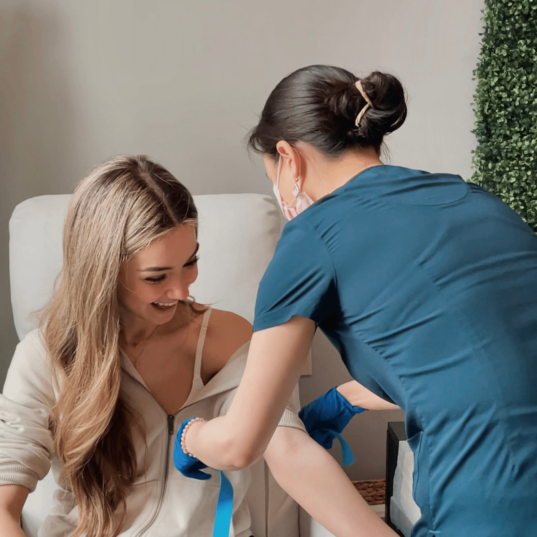 IV nurse helping set young woman up with IV treatment