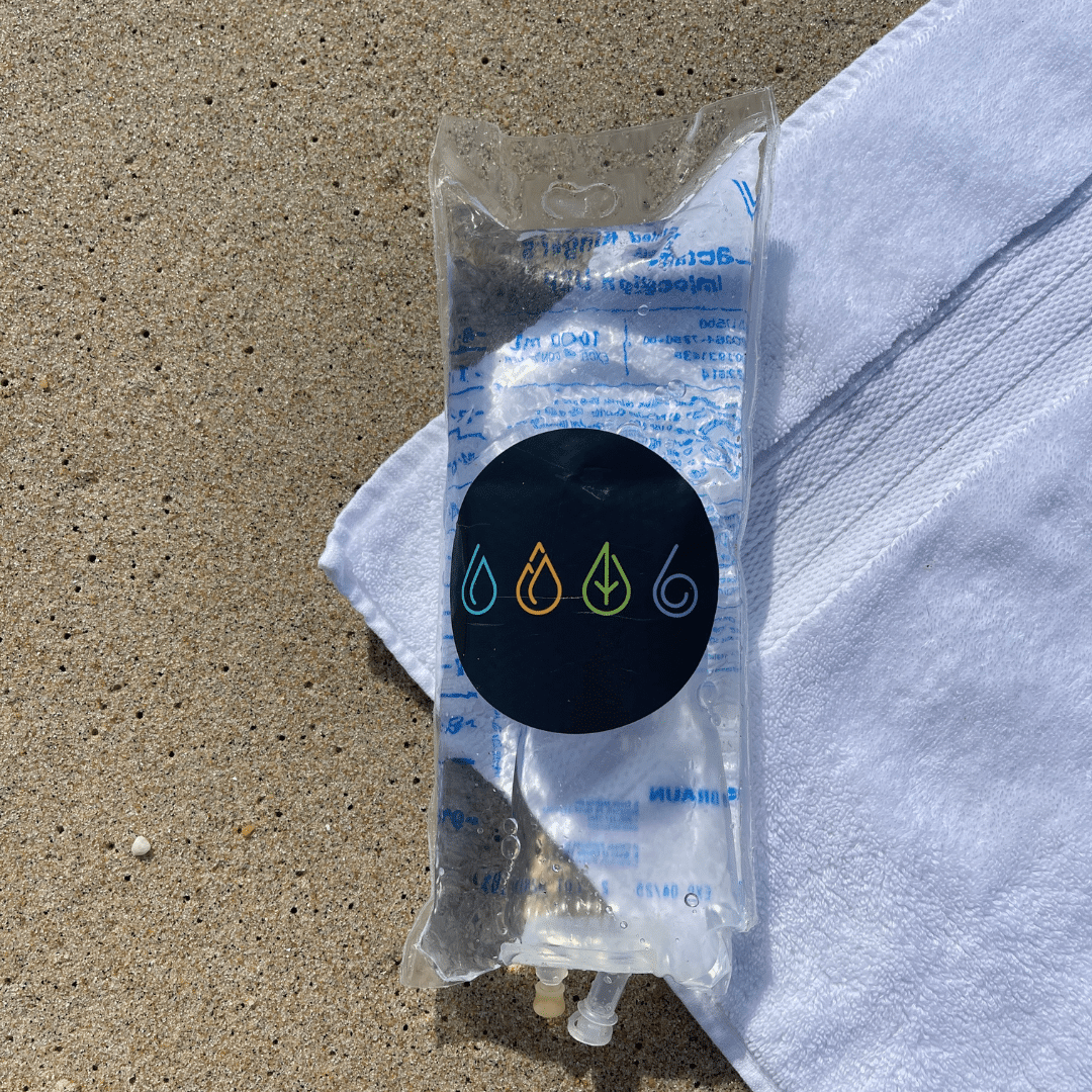 An IV bag on the sand with a towel
