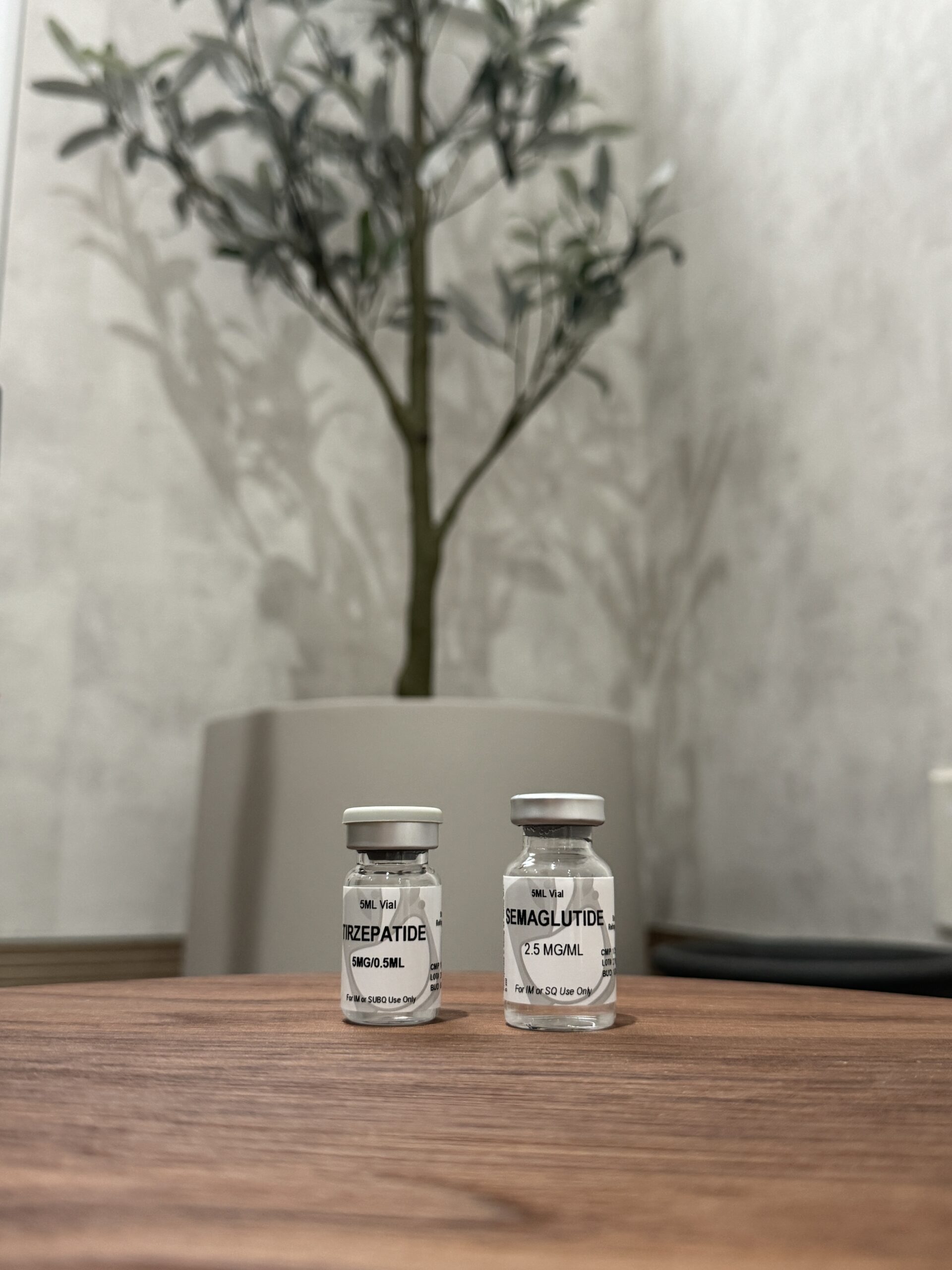 Two small glass bottles on a wooden table; one reads 