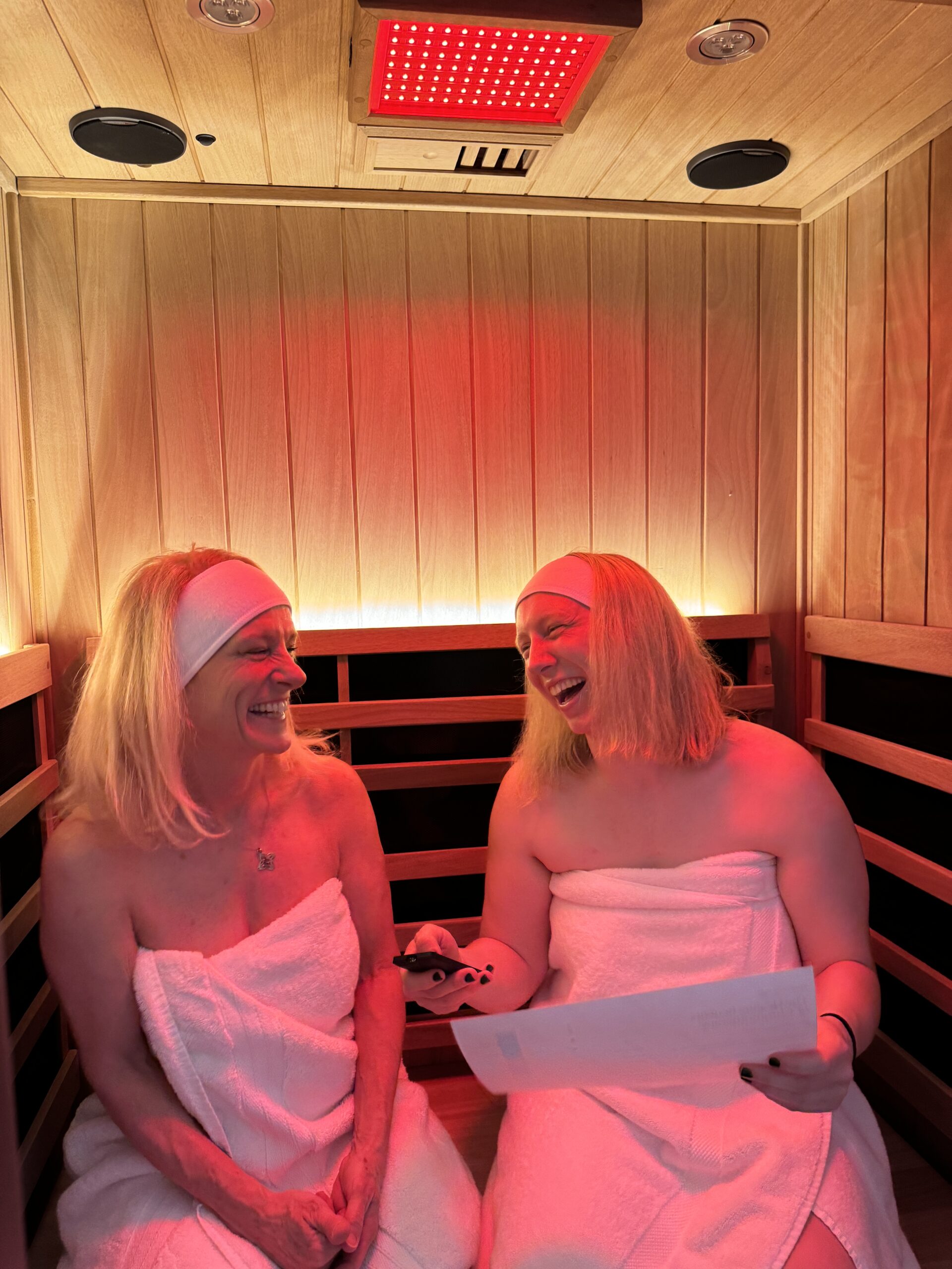 Two blonde women laughing as they enjoy an infrared sauna