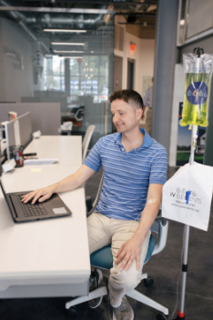 A person working on their laptop while they get IV therapy at the Asbury Drip Lounge