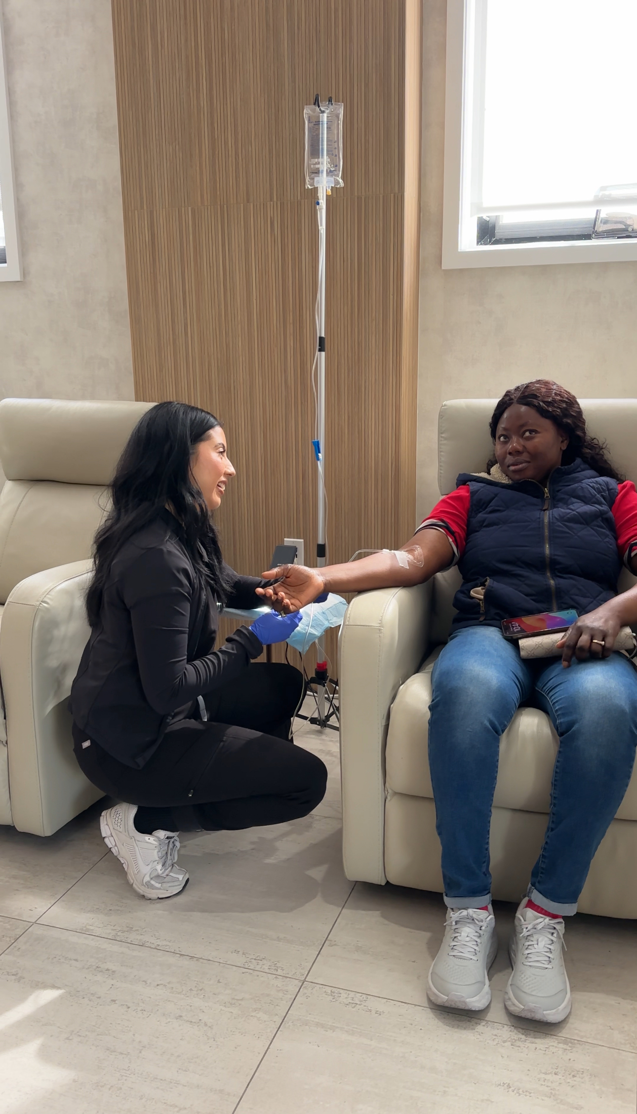 nurse speaking with patient who is sitting and receiving IV