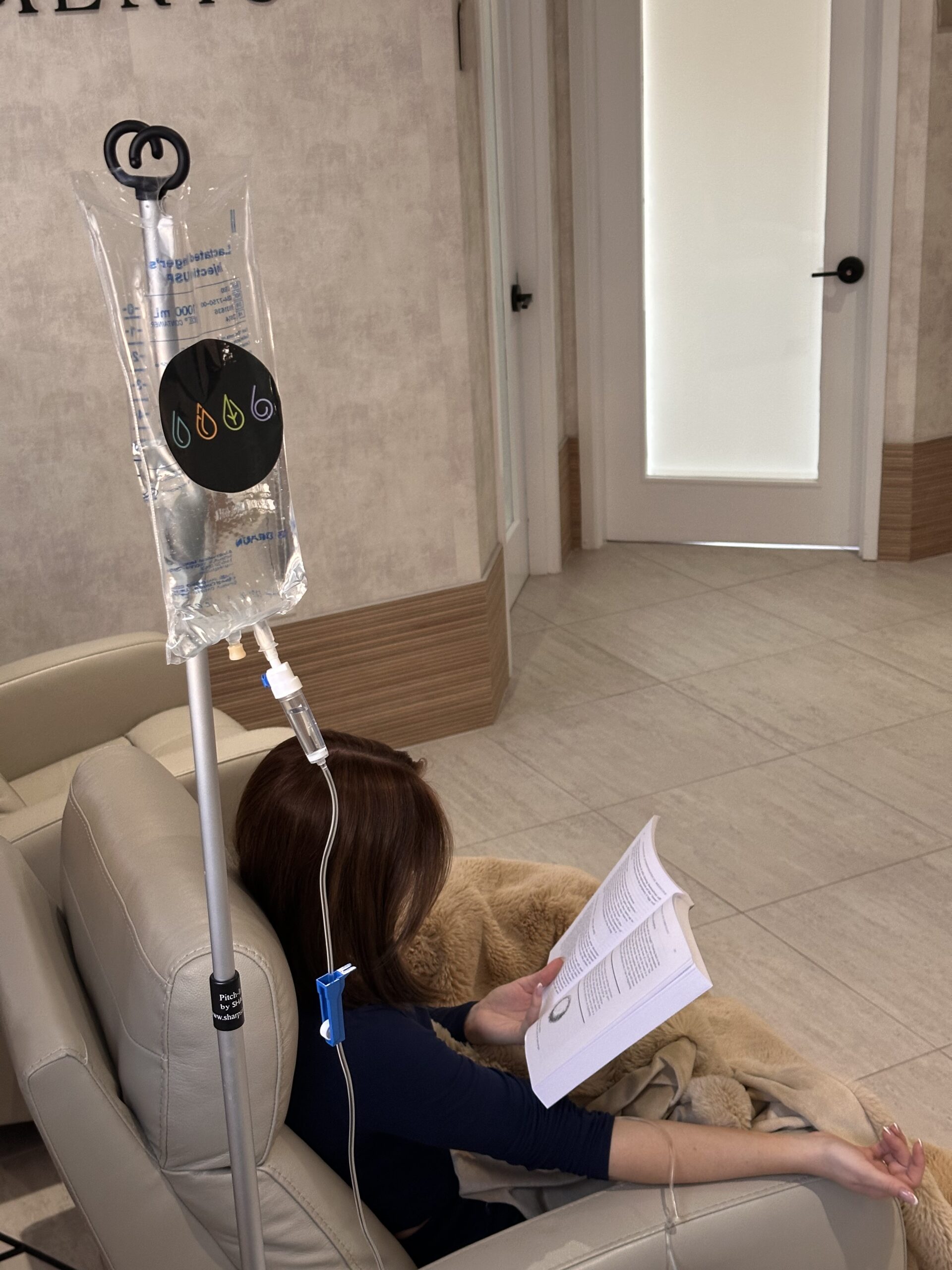 Patient reading book while receiving IV treatment