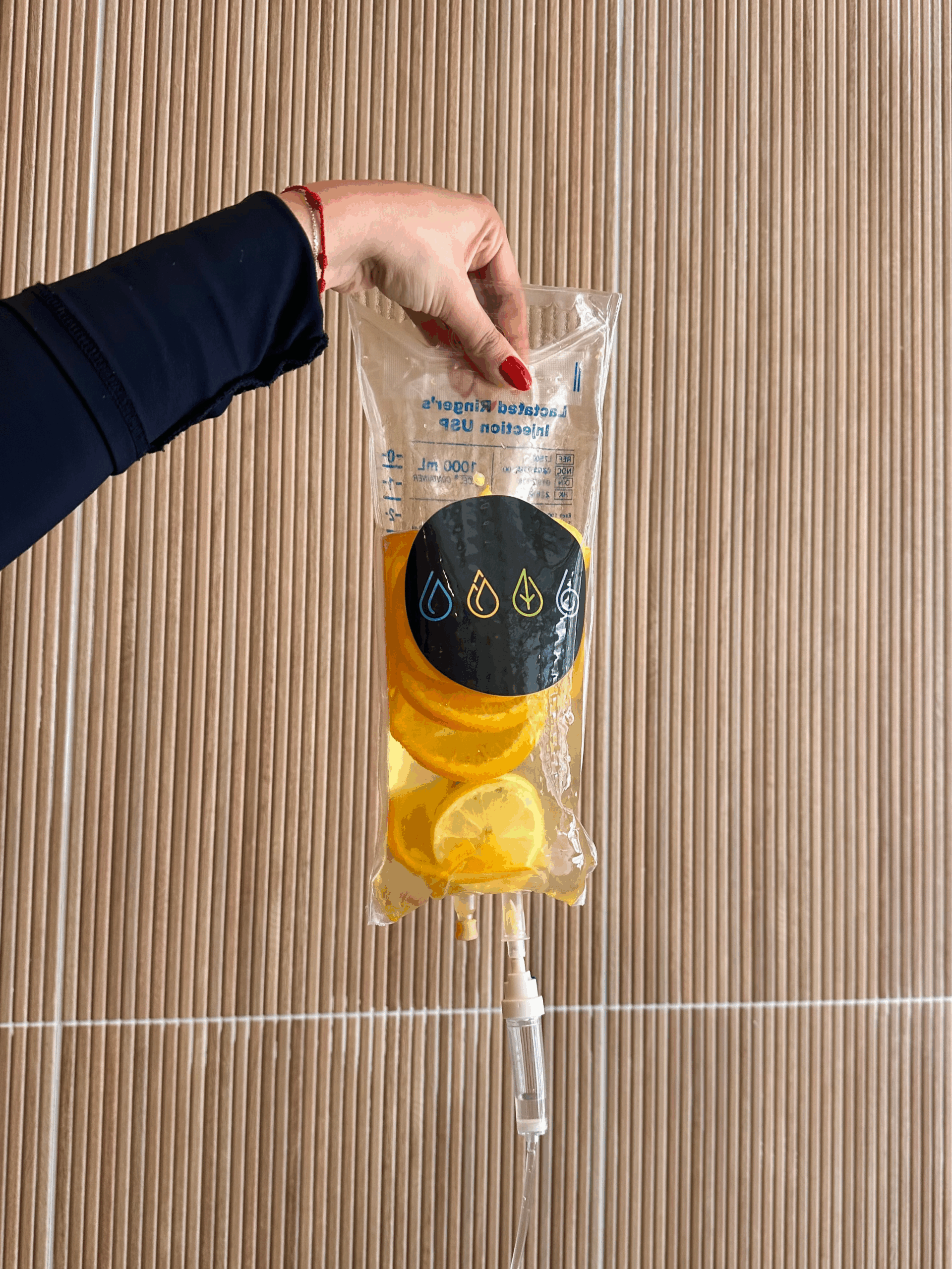 Hand holding IV bag with sliced oranges inside