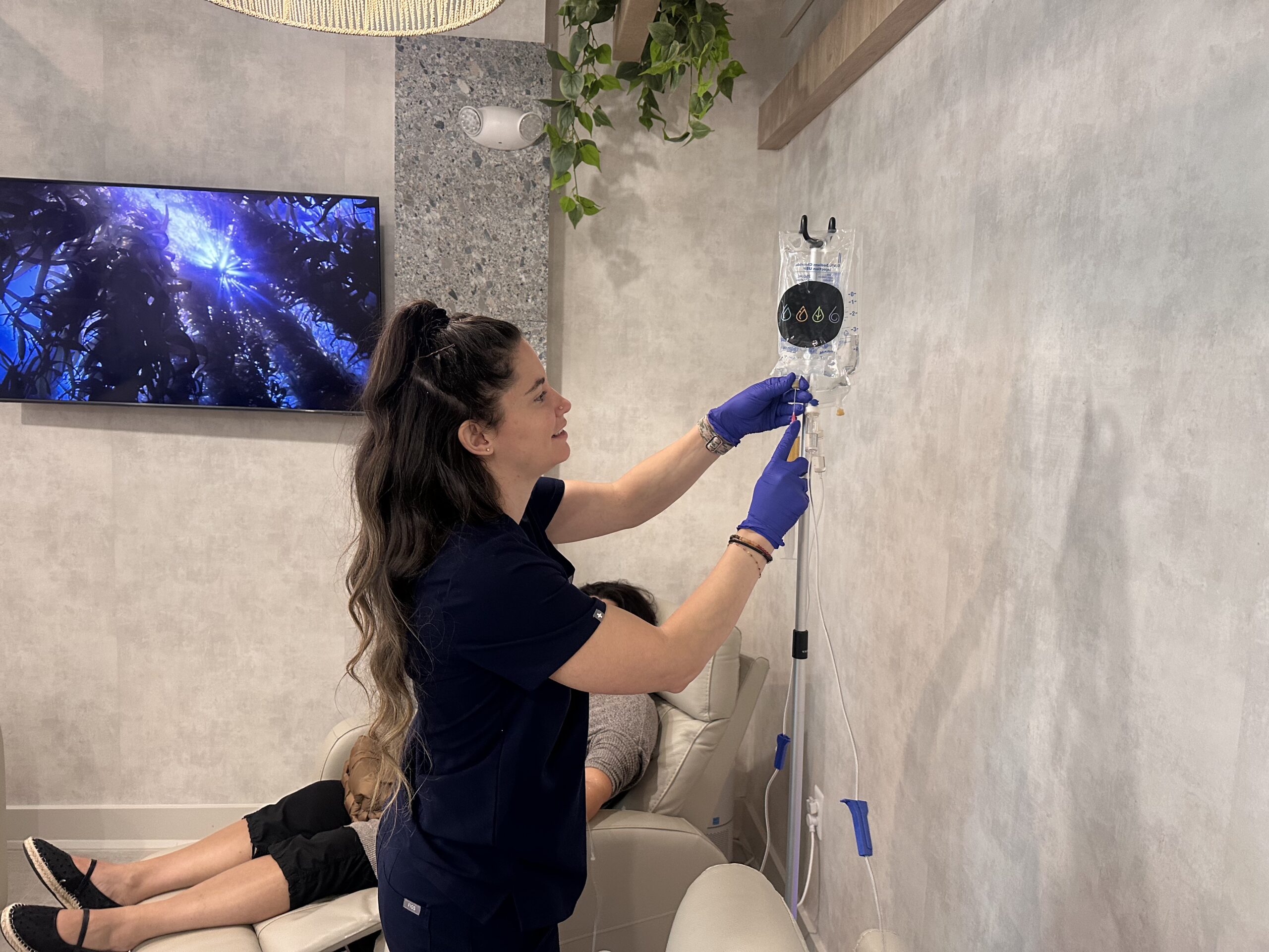 Nurse adding to IV Bag while patient reclines in the background