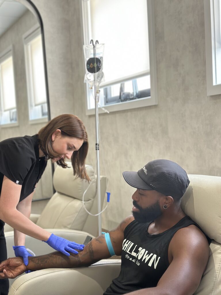 Nurse giving IV to patient sitting in chair.