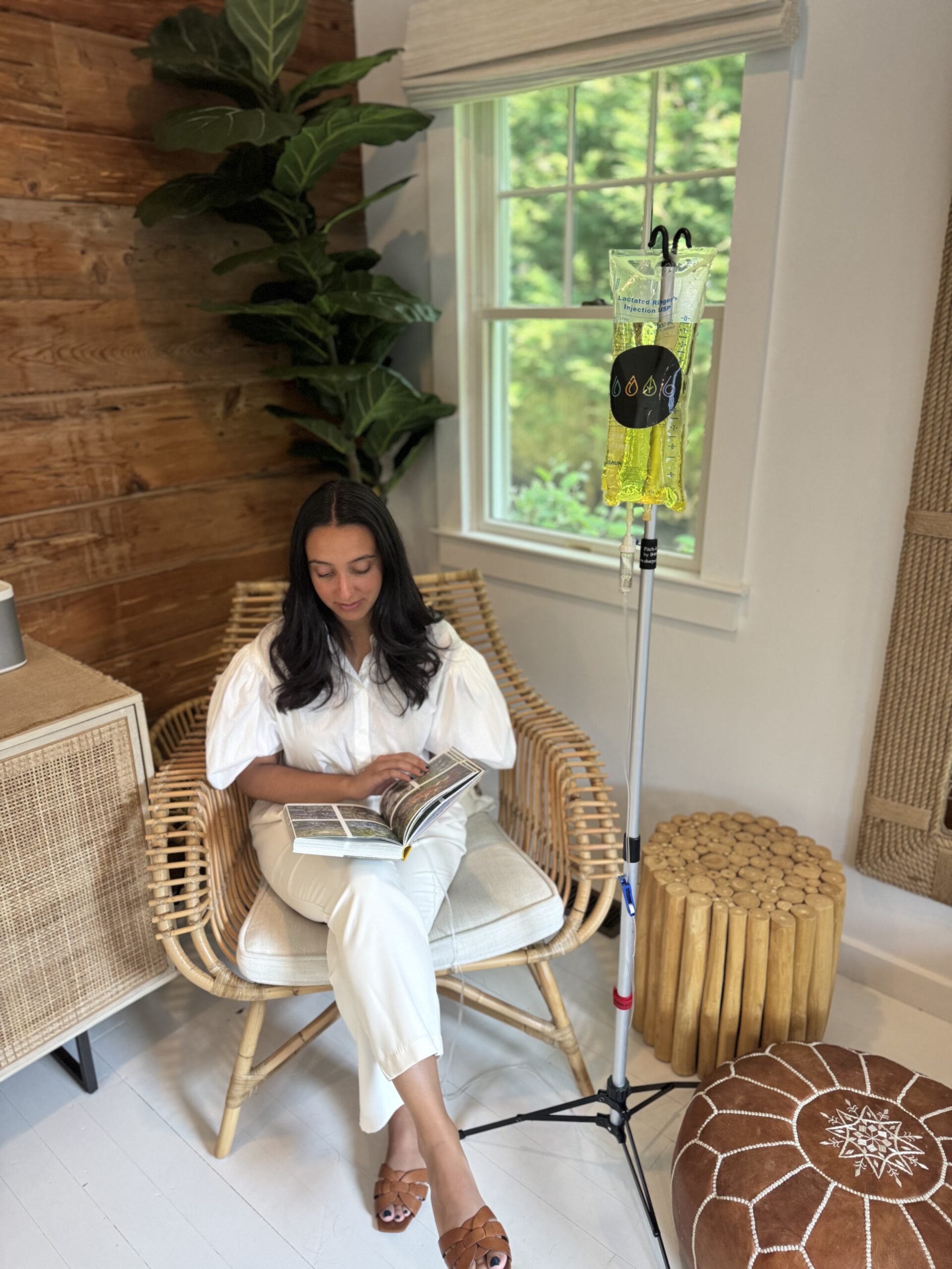 women sitting in chair reading book receiving IV treatment