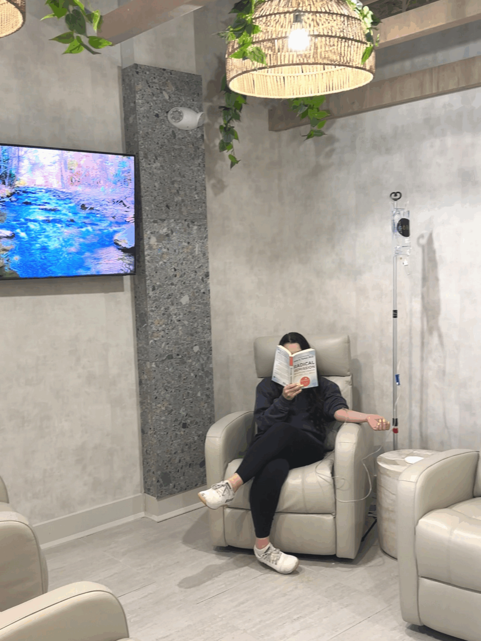 Patient receiving IV while sitting in chair reading book